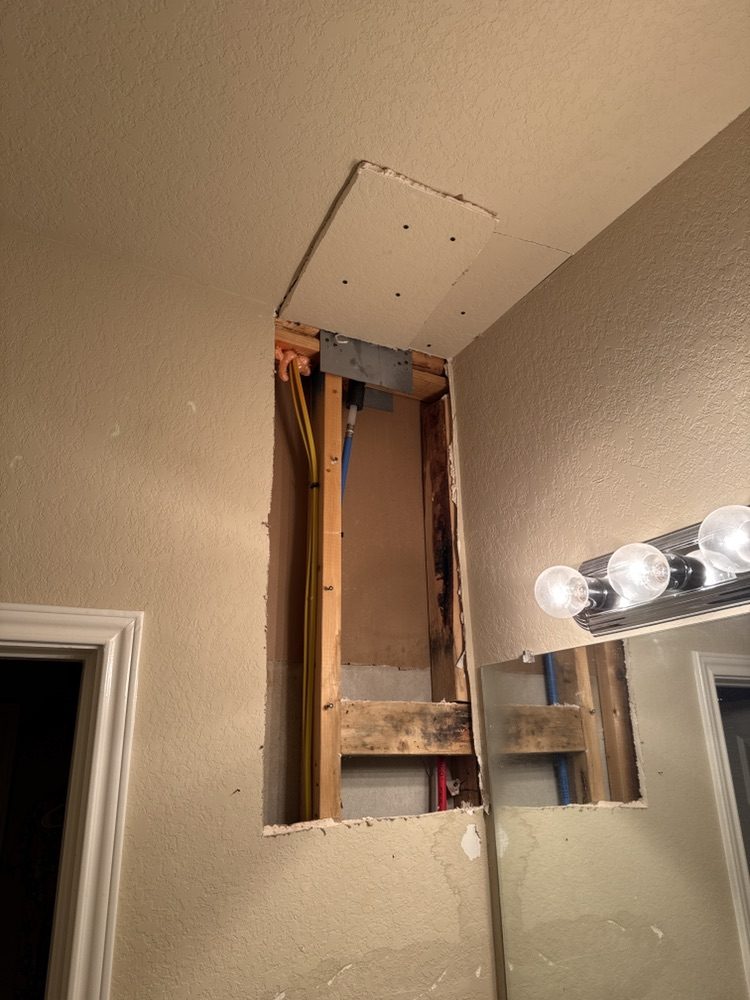 Bathroom ceiling and wall opened with plumbing exposed for water-damage repair